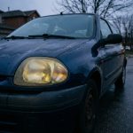 Phares jaunis et oxydés d'une Renault Clio 2 ancienne, visibilité nocturne réduite par l'usure des optiques