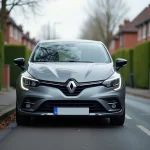 Renault Clio 5 grise métallisée garée dans une rue résidentielle, vue en perspective trois quarts avant