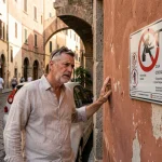 Touriste examinant un panneau ZTL dans une ruelle historique italienne pavée
